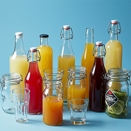 gastronomy Mood picture: glasses and bottles filled with juices and fruit against a light blue background