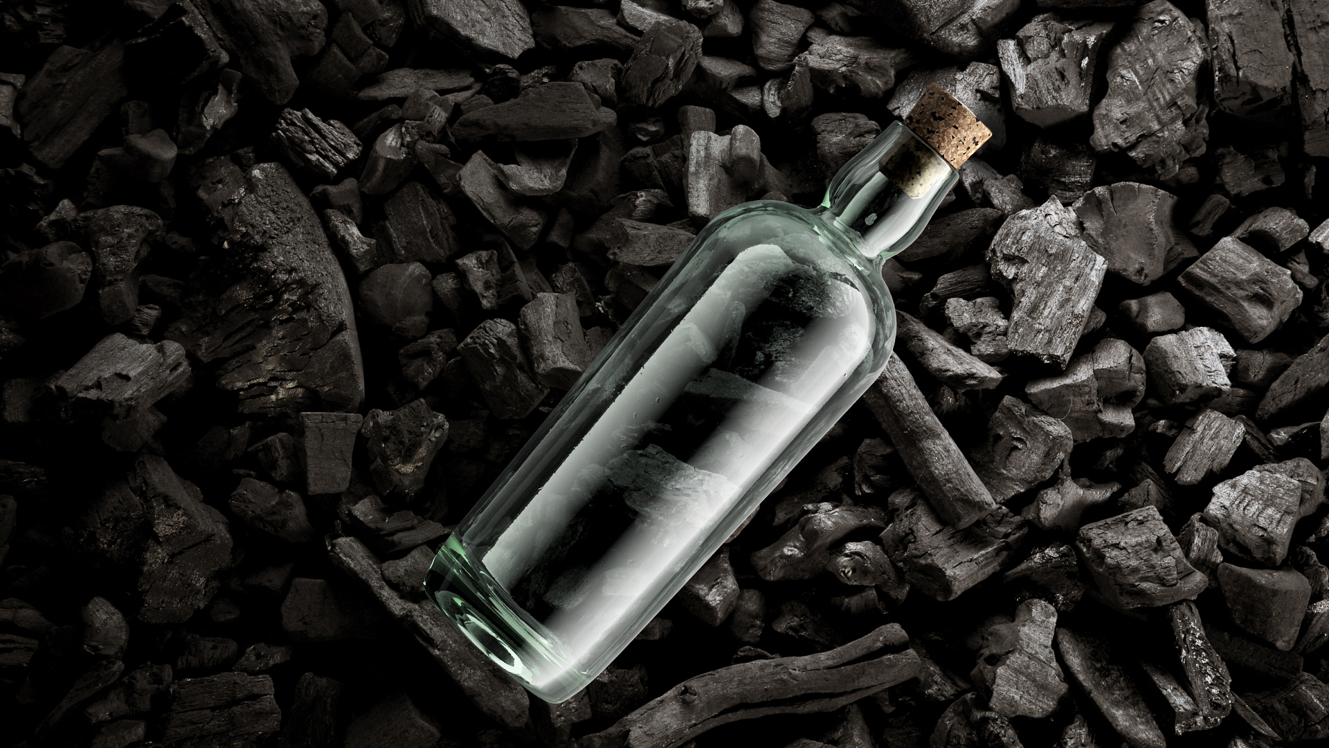 Estal Corkcoal closures Mood picture: a transparent glass bottle of the brand Estal with Corkcoal closure lies on a background of coal pieces