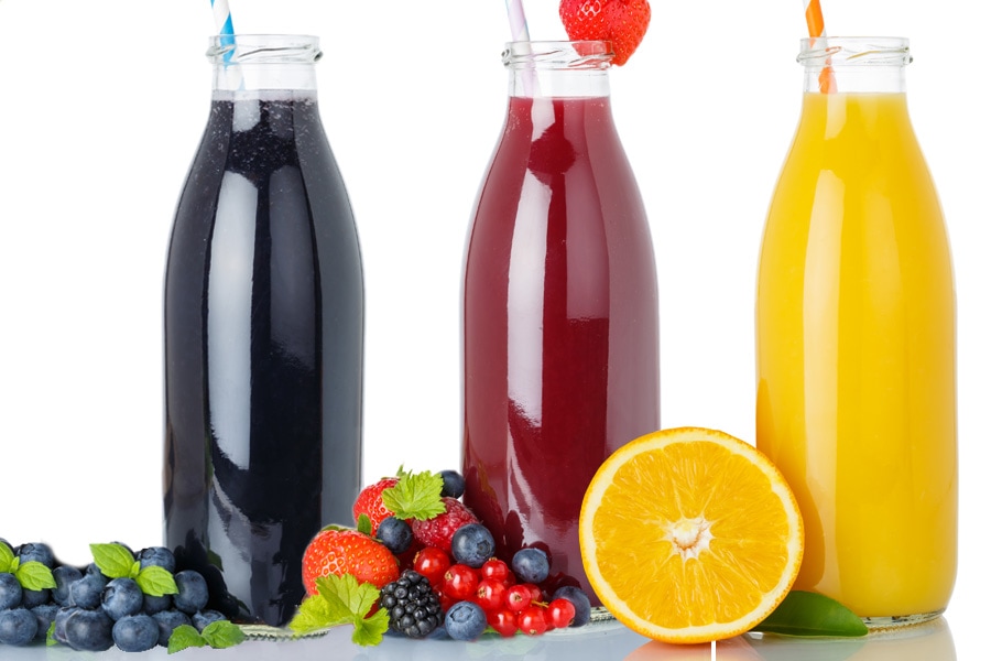 Group of three transparent wide-mouth bottles filled with black, red and yellow smoothies and a straw each, decorated with fruits