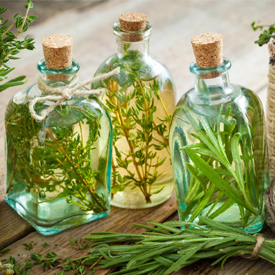Three clear glass bottles filled with flavored oil, closed with a cork